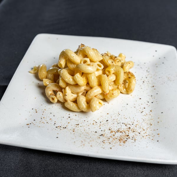 Creamy Southern Fresh macaroni and cheese, seasoned with pepper, on a white square plate.