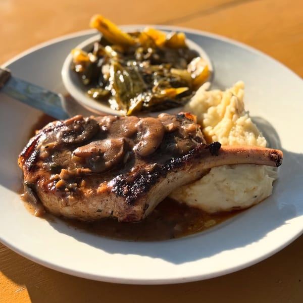 Southern Fresh pork chop with mushroom gravy, mashed potatoes, and a side of collard greens.