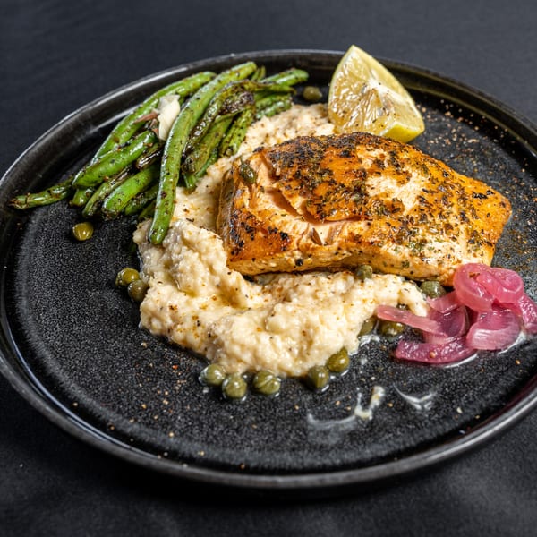 Southern Fresh salmon with grits, green beans, pickled onions, capers, and a lemon wedge.